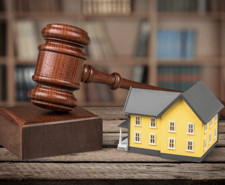 A wooden gavel sitting next to a yellow house.