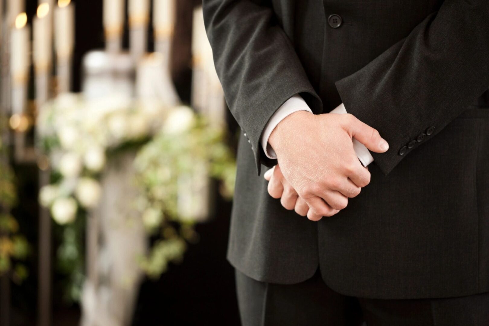 A man in black suit and white shirt holding hands.