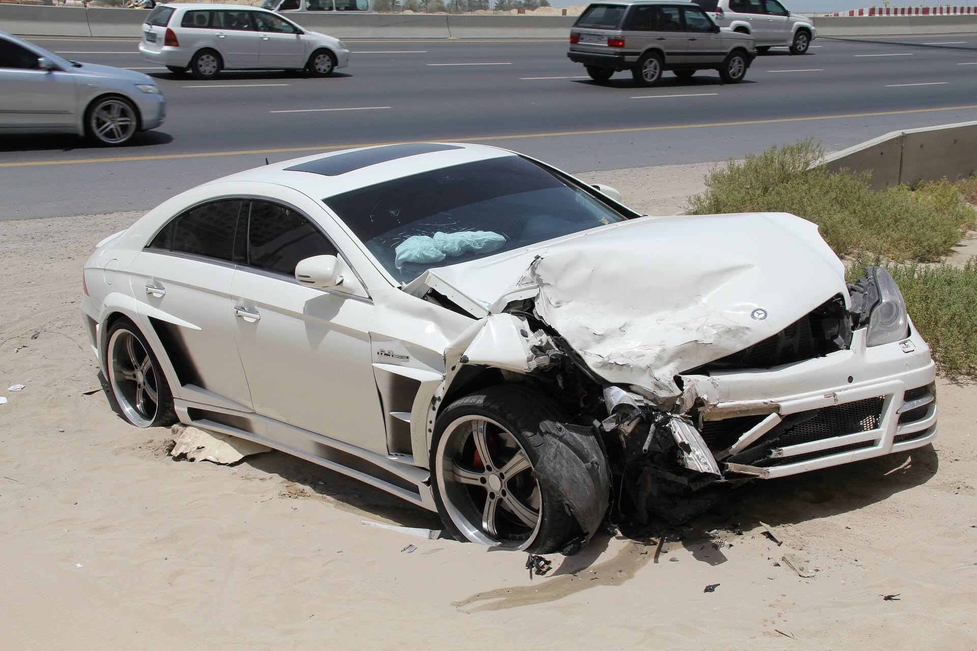 A white car that has been smashed in the road.
